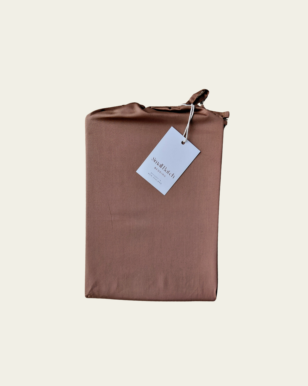 Chocolate brown cotton fabric product bag with a Small Batch Bedding tag on a light beige background