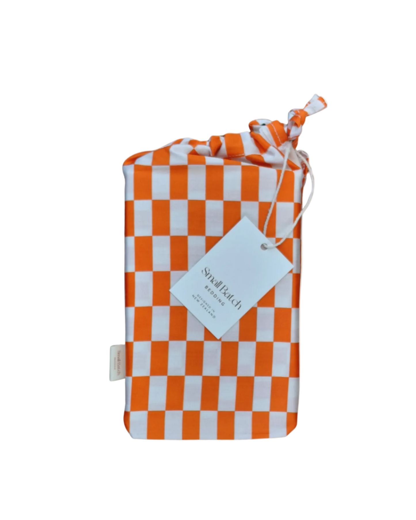Tomato red orange and light checkered cotton product bag with a Small Batch Bedding tag on a light beige background.