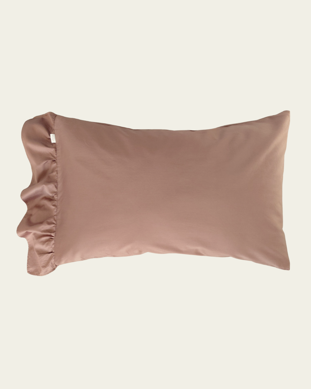Brown cotton pillowcase with ruffled edge on a beige background