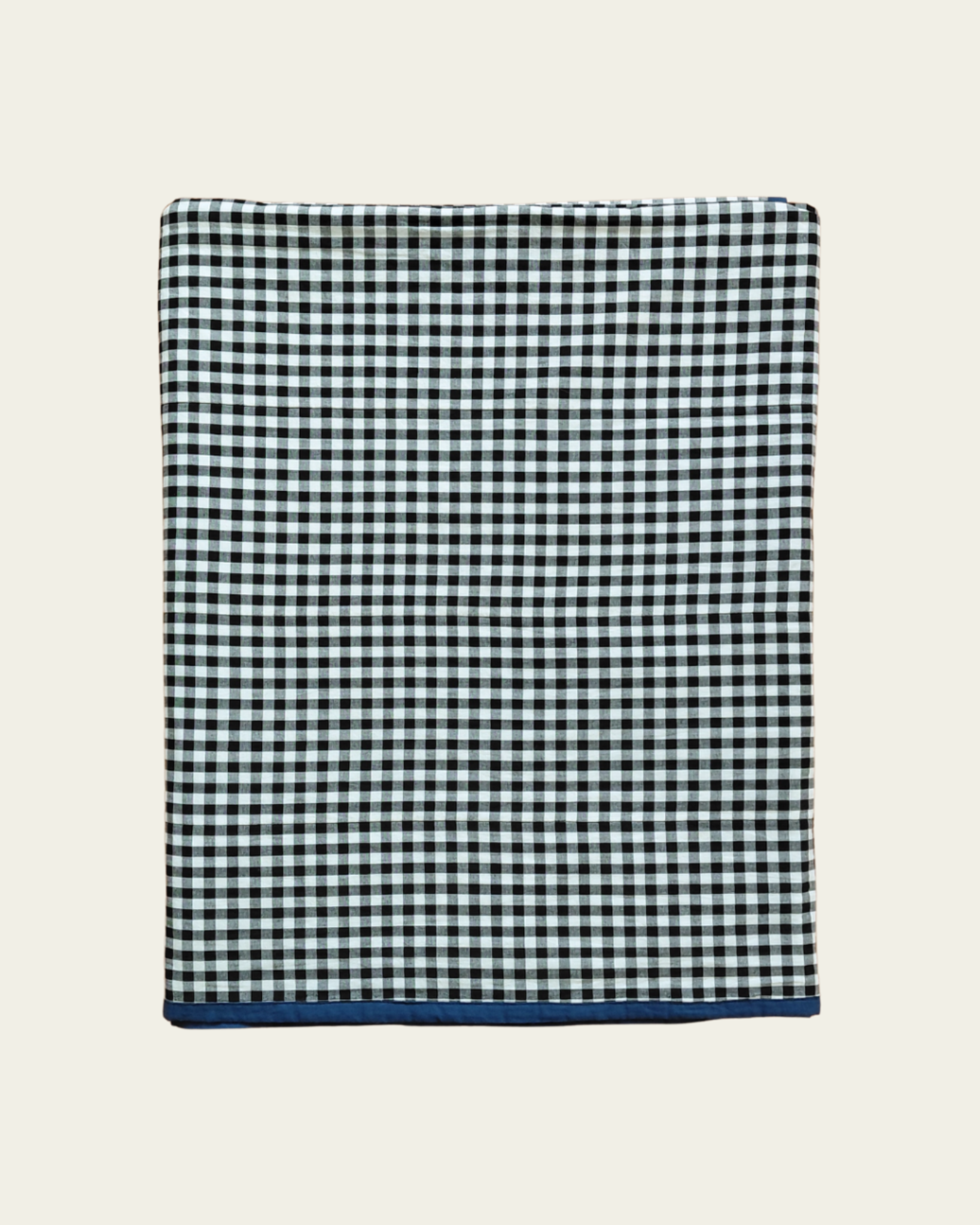 Black and white checkered gingham cotton blanket revers side with a blue border on a beige background