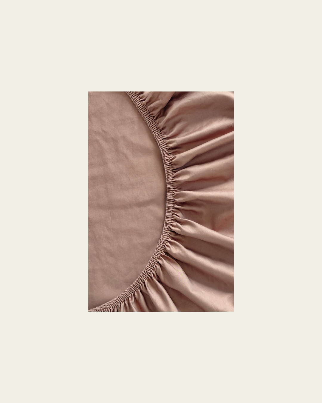 Close-up of a fitted chocolate brown cotton sheet with a  plain background