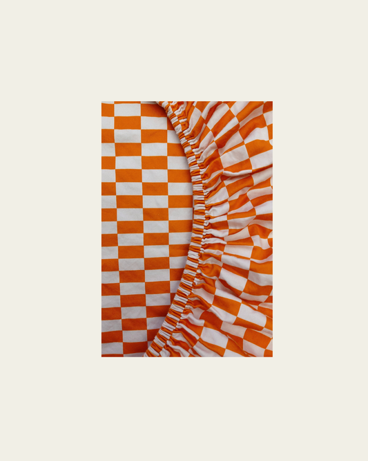Checkered tomato tile patterned cotton fitted sheet product shot by Small Batch Bedding on a beige background