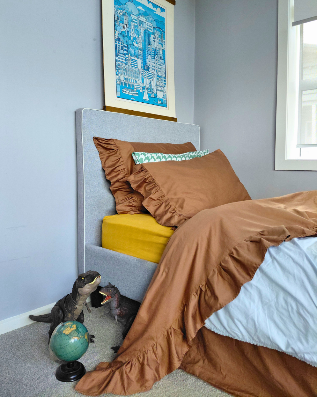 Bedroom with chocolate brown cotton bedding with ruffle, gray headboard, and framed artwork on wall.