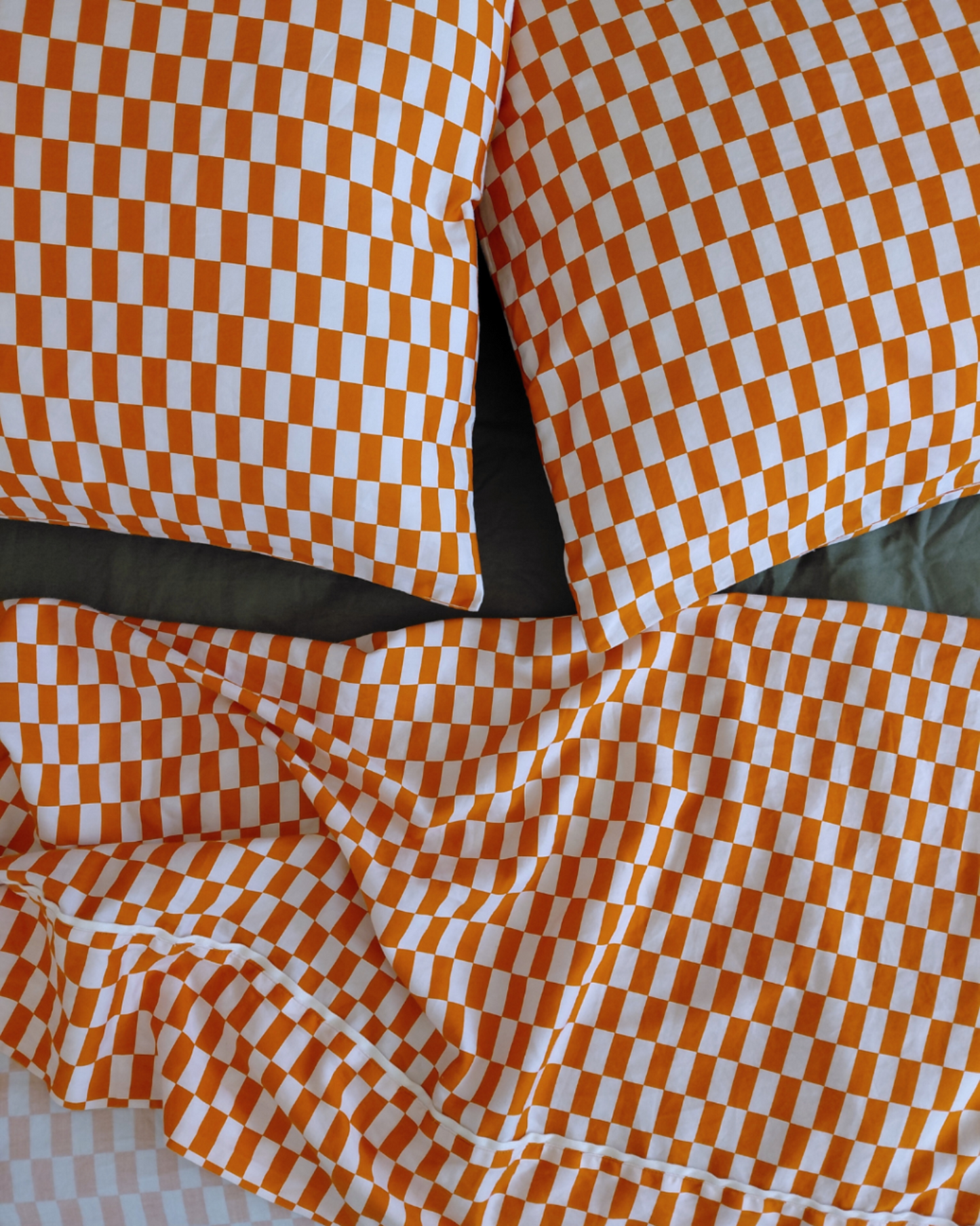 Tomato red orange tile design bedding by Small Batch Bedding on made bed with green fitted sheet featuring Kid's Flat Sheet and pillowcase set. 