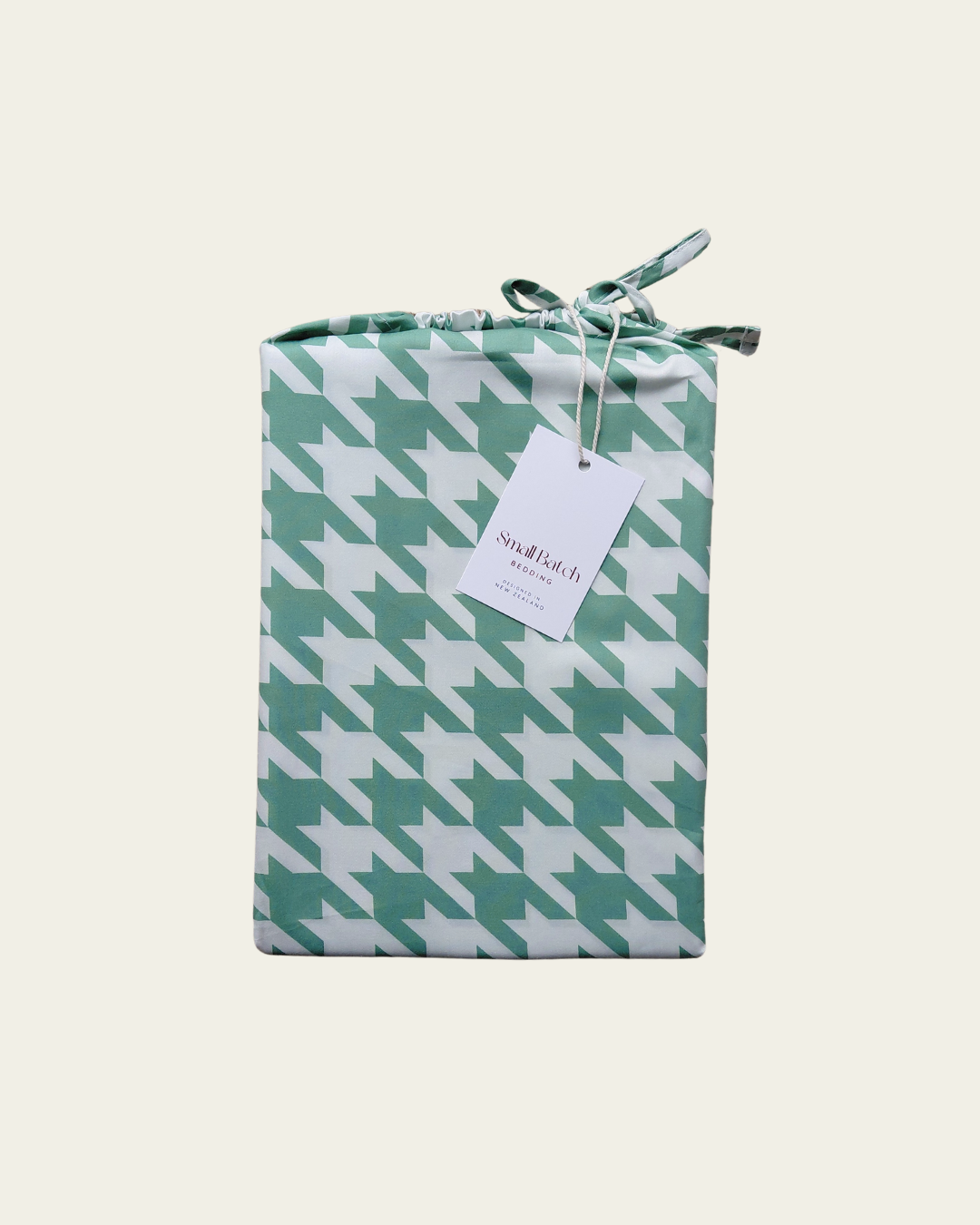 Gift bag packaging with green and white houndstooth pattern and a visible brand tag on a white background
