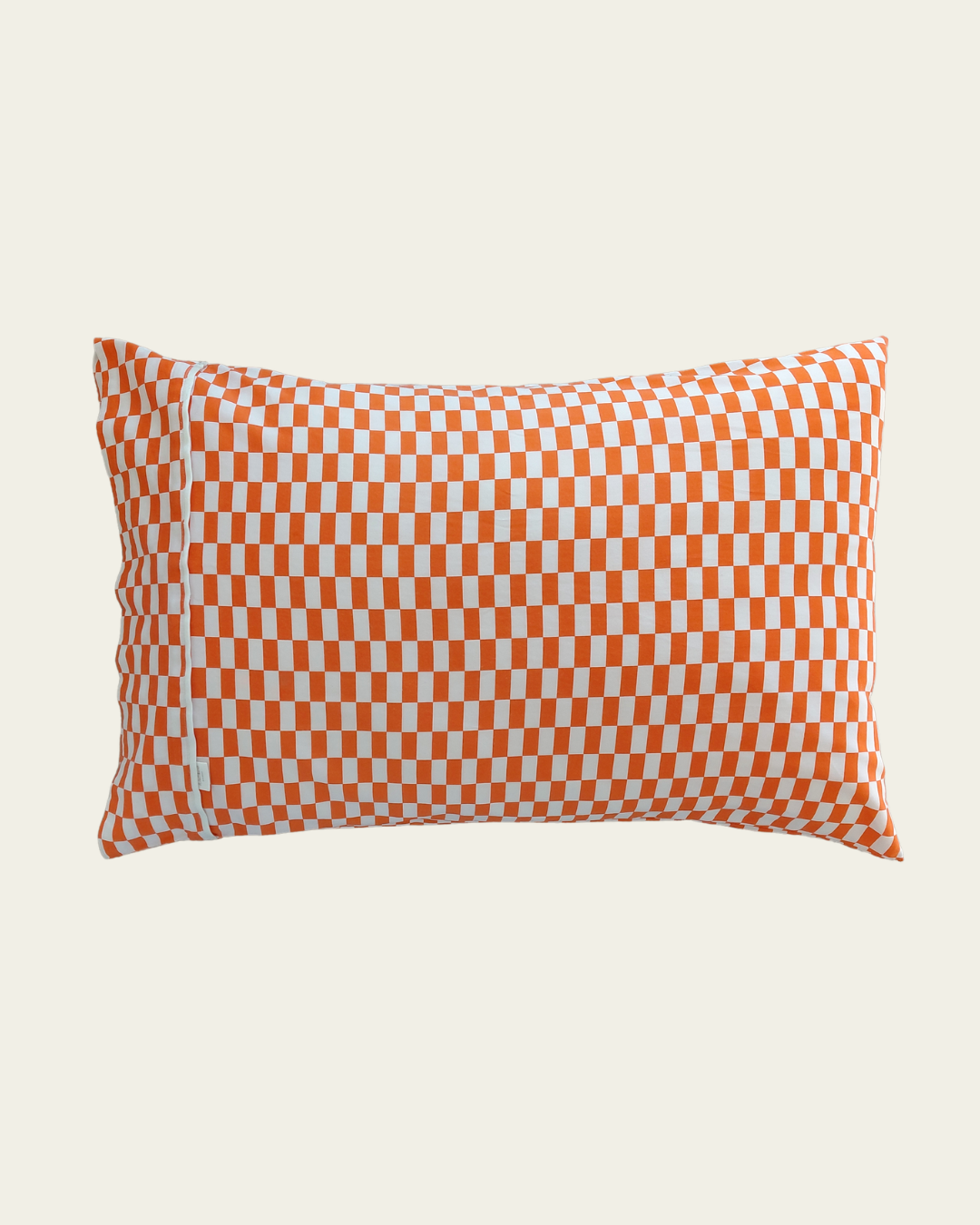 Orange and white tomato tile checkered pillow by Small Batch Bedding on a beige background